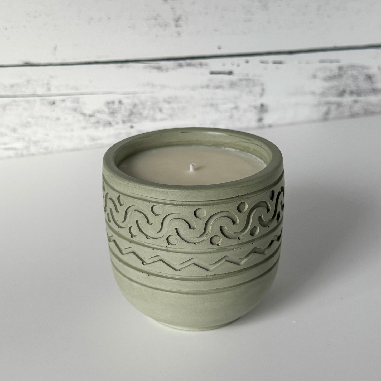 Forest Calm Candle with design on side of moss colored concrete jar.