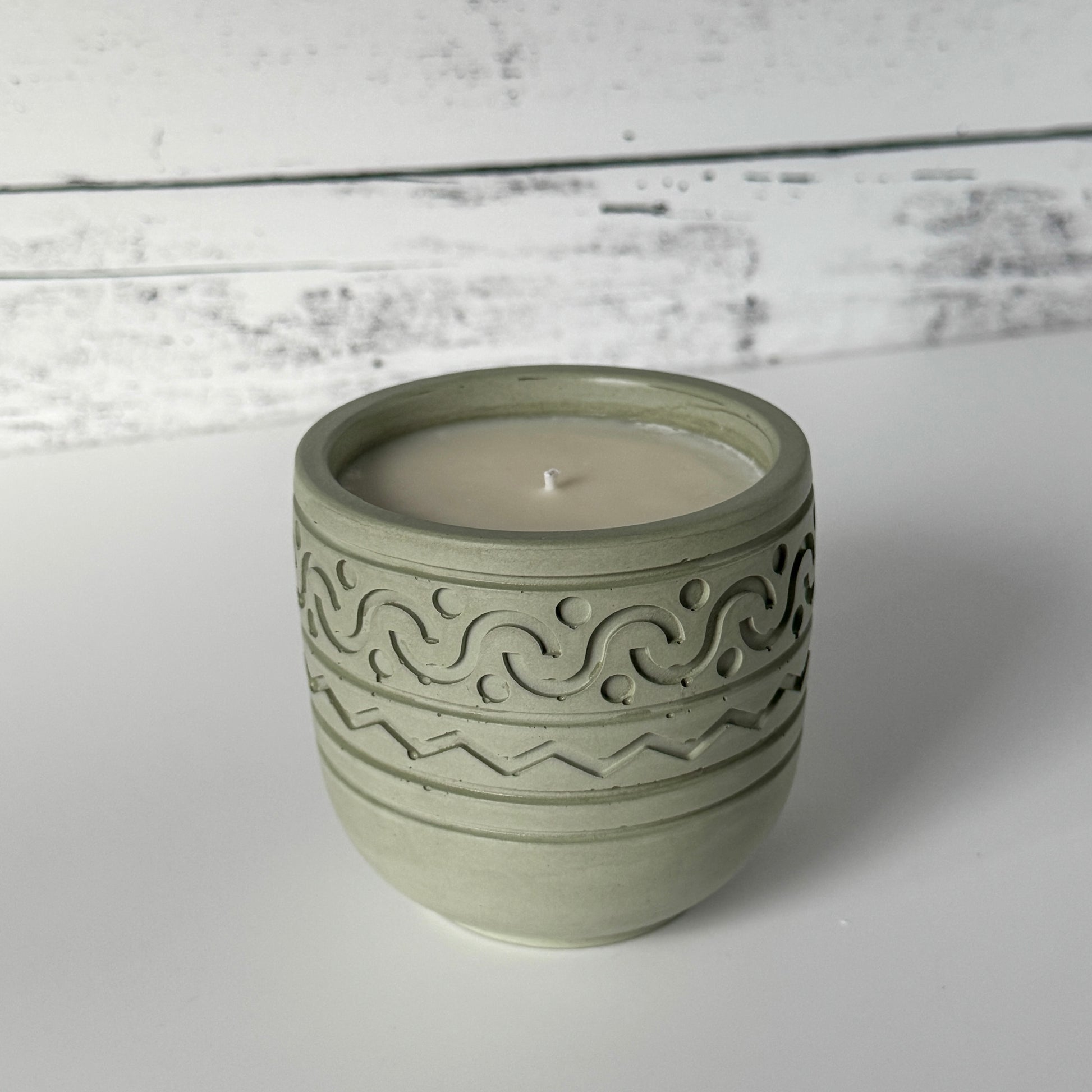 Forest Calm Candle with design on side of moss colored concrete jar.
