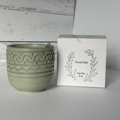 Forest Calm Candle in a moss colored concrete jar with packaging in the background